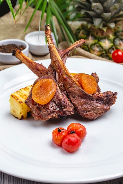 Foto gratuita vista frontal de costillas de cordero kebab con albaricoques secos y tomates cherry