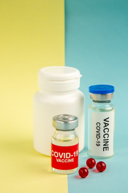 Vista frontal covid- vacunas sobre fondo amarillo-azul color pandémico salud covid- fármaco virus hospital ciencia