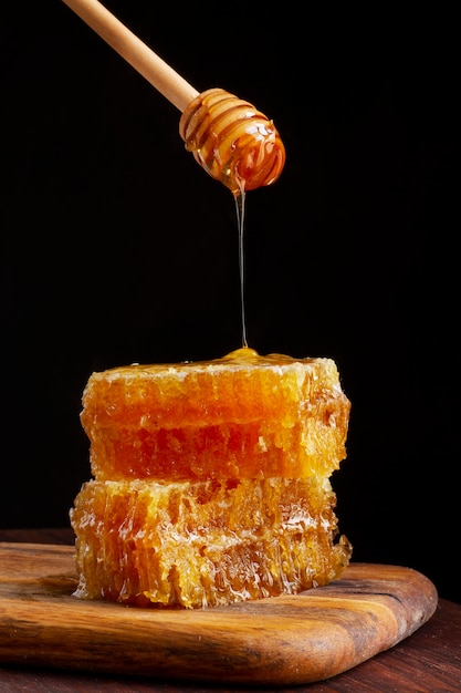 Vista frontal del cucharón de miel goteando miel en panal