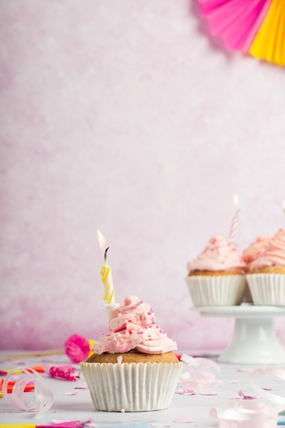 Vista frontal de cupcake de cumpleaños con hielo y velas encendidas