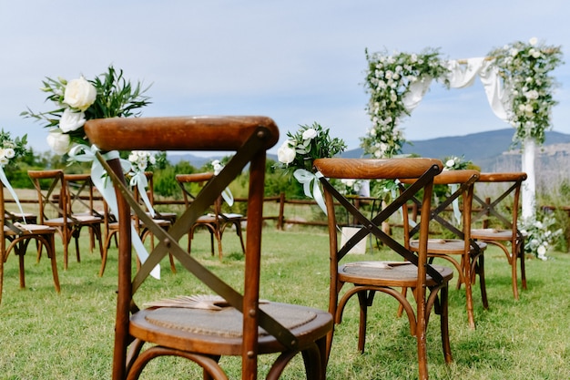 Foto gratuita vista frontal de la decoración floral de eustomas blancas y ruscus de sillas chiavari marrones al aire libre y arco ceremonial de boda