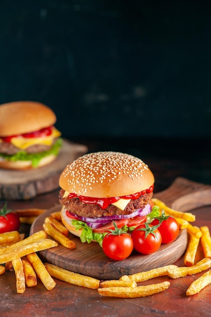 Foto gratuita vista frontal deliciosa carne hamburguesa con queso con papas fritas sobre fondo oscuro cena hamburguesa bocadillo comida rápida sándwich plato tostado