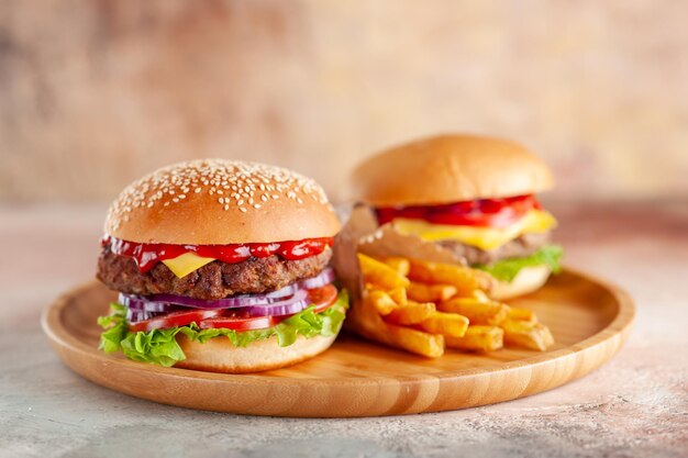 Vista frontal deliciosa carne hamburguesa con queso con papas fritas en la tabla de cortar fondo claro ensalada cena comida rápida sándwich plato hamburguesa merienda