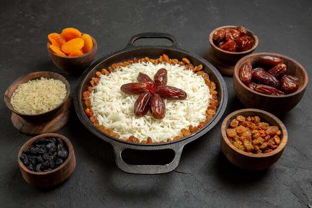 Vista frontal deliciosa comida de arroz cocido plov con pasas en la superficie oscura comida comida cena oriental de arroz