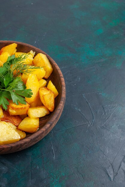 Vista frontal de la deliciosa comida de patatas en rodajas cocidas con verduras dentro de la placa marrón sobre la superficie azul oscuro