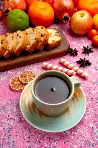 Vista frontal deliciosa composición de frutas con tortas en rodajas y té en el escritorio rosa