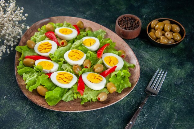 Vista frontal deliciosa ensalada de huevo se compone de aceitunas y ensalada verde sobre fondo oscuro