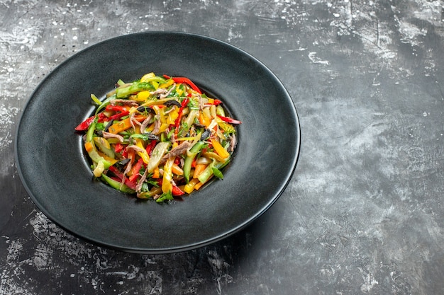 Vista frontal deliciosa ensalada de verduras dentro de la placa sobre la mesa gris