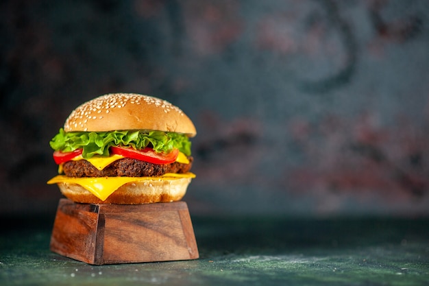 Vista frontal deliciosa hamburguesa con queso sobre fondo oscuro