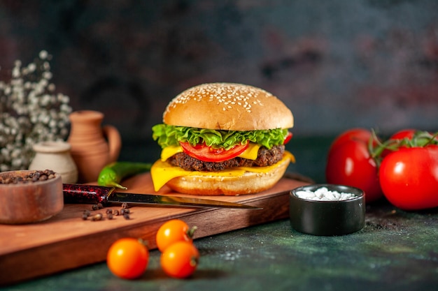 Vista frontal deliciosa hamburguesa con queso sobre fondo oscuro