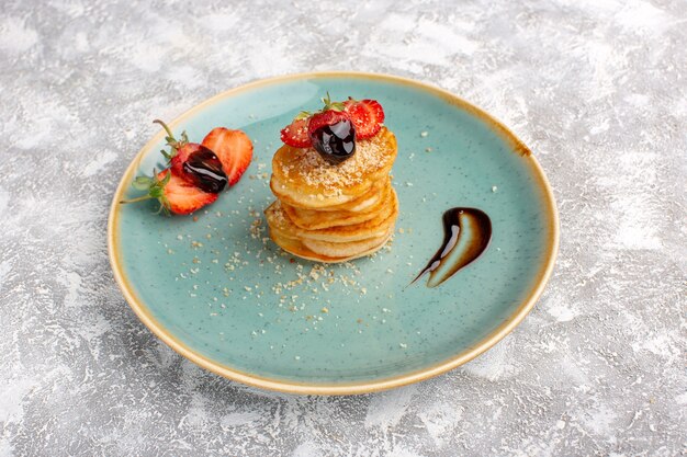 Vista frontal deliciosa pastelería dulce con fresas dentro de la placa sobre la mesa blanca, pastelería dulce de azúcar horneado