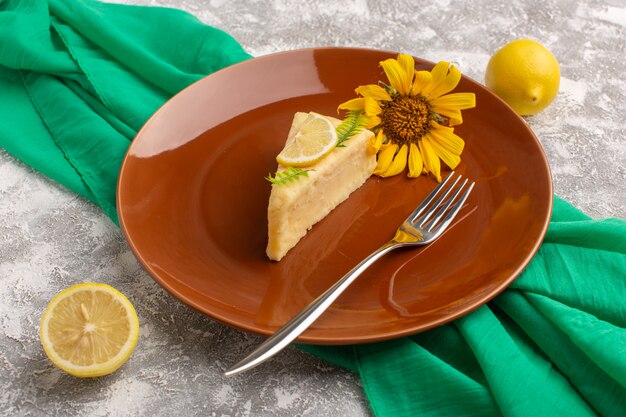 Vista frontal de la deliciosa rebanada de pastel con limón dentro de la placa marrón en la superficie de la luz