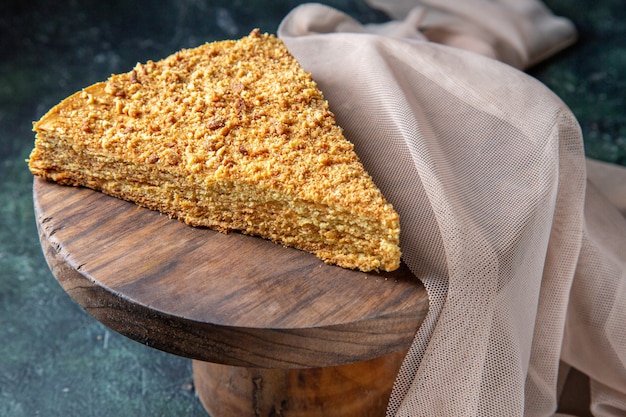 Vista frontal deliciosa rebanada de pastel de miel en la superficie oscura del tablero de madera redonda