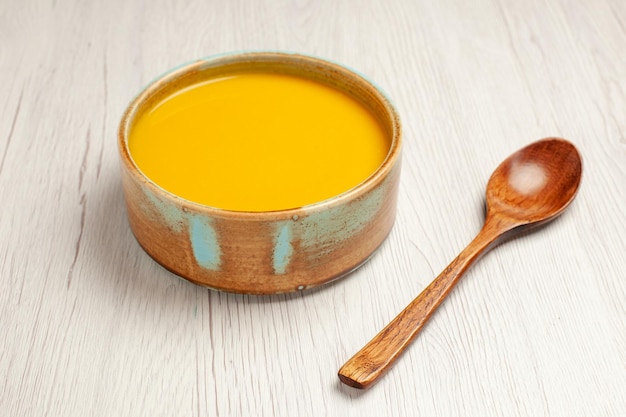 Vista frontal deliciosa sopa de crema sopa de color amarillo sobre un escritorio blanco sopa salsa comida crema plato de cena
