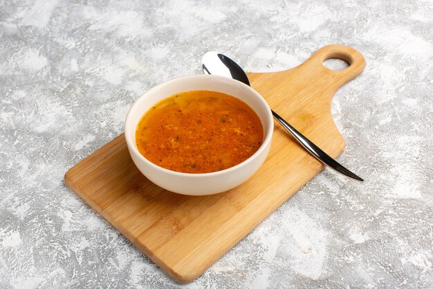 Foto gratuita vista frontal de la deliciosa sopa dentro de la placa en el escritorio de luz gris