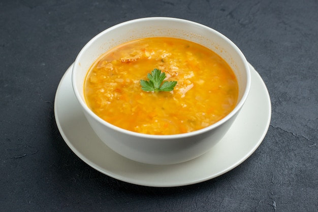 Vista frontal deliciosa sopa dentro de un plato blanco sobre una superficie oscura