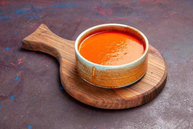 Vista frontal deliciosa sopa de tomate cocinada con tomates rojos frescos en el espacio oscuro