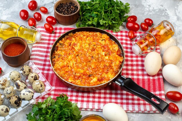 Vista frontal deliciosa tortilla con tomates fritos alrededor de verduras y verduras sobre fondo blanco desayuno pan leche almuerzo