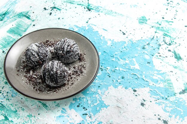 Vista frontal deliciosas bolas de chocolate pasteles de chocolate redondos formados con glaseado sobre la superficie azul pastel hornear galleta dulce azúcar chocolate