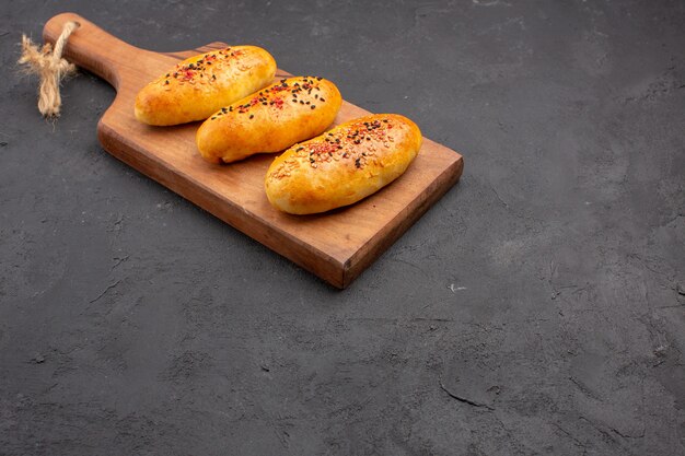 Vista frontal deliciosas empanadas al horno recién salido del horno sobre fondo gris horno de tarta masa de pastelería pastel de carne hornear