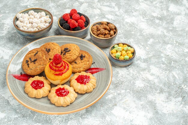 Vista frontal deliciosas galletas de arena con galletas y dulces en el espacio en blanco