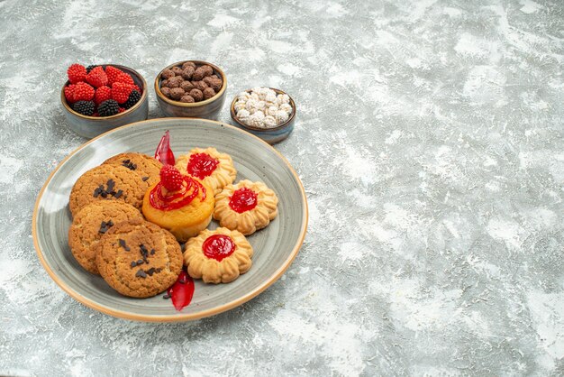 Vista frontal deliciosas galletas de arena con galletas y dulces en el espacio en blanco