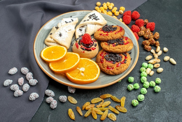 Vista frontal deliciosas galletas de azúcar con pasteles y rodajas de naranja en la superficie oscura galleta de azúcar dulce pastel de té galleta