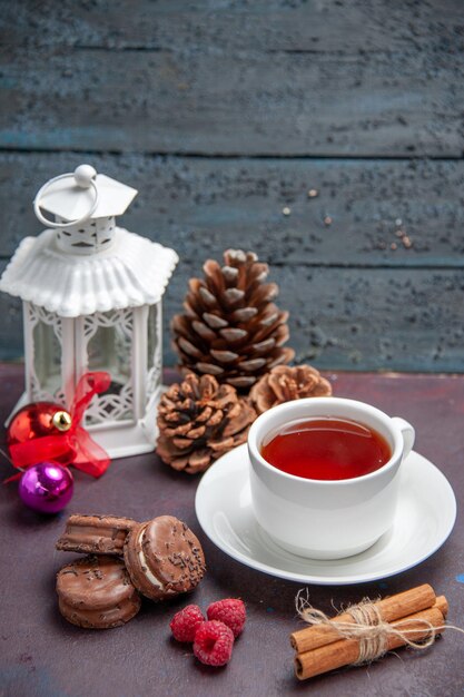 Vista frontal de deliciosas galletas de chocolate con una taza de té en el fondo oscuro pastel de galletas pastel de té dulce galleta