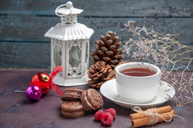 Vista frontal de deliciosas galletas de chocolate con una taza de té en el fondo oscuro pastel de galletas pastel de té dulce galleta