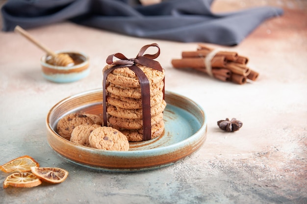 Vista frontal deliciosas galletas dulces atadas con un lazo dentro de la placa sobre una superficie clara postre masa té dulce galleta pastel horizontal