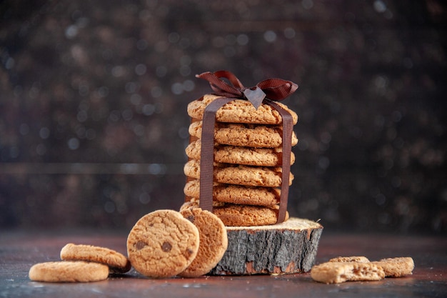 Vista frontal deliciosas galletas dulces atadas con lazo sobre fondo oscuro postre azúcar té galleta dulce