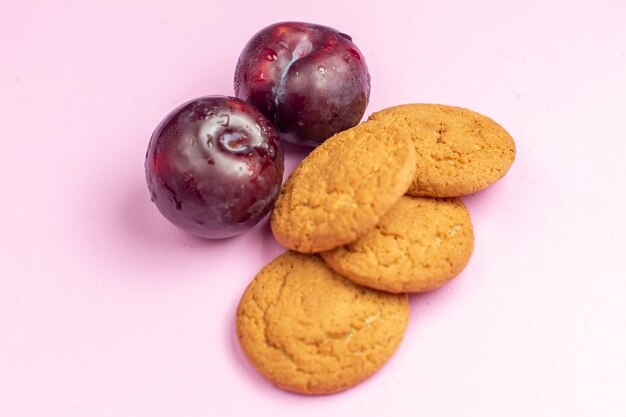 Vista frontal deliciosas galletas dulces horneadas con ciruelas en el fondo rosa galleta dulce azúcar hornear té