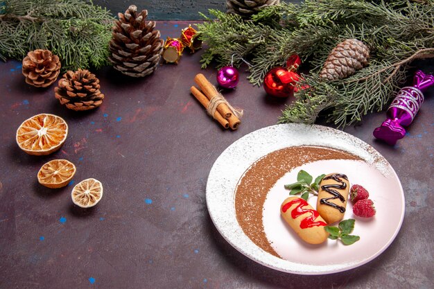 Vista frontal deliciosas galletas dulces con juguetes navideños en el espacio oscuro