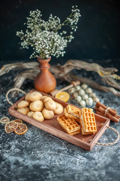 Vista frontal deliciosas galletas dulces con pequeños pasteles en pastel de nuez de galleta de azúcar de pastel dulce de color gris claro