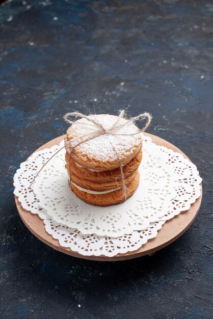 Vista frontal deliciosas galletas sándwich atadas deliciosas en el pastel de escritorio azul oscuro