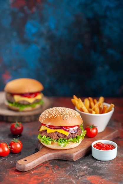 Foto gratuita vista frontal deliciosas hamburguesas con queso de carne con tomates y papas fritas sobre un plato de fondo oscuro comida rápida sándwich tostadas merienda cena