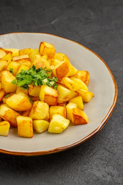 Vista frontal deliciosas papas fritas dentro de la placa en la mesa oscura cena de color de comida de aceite de mesa