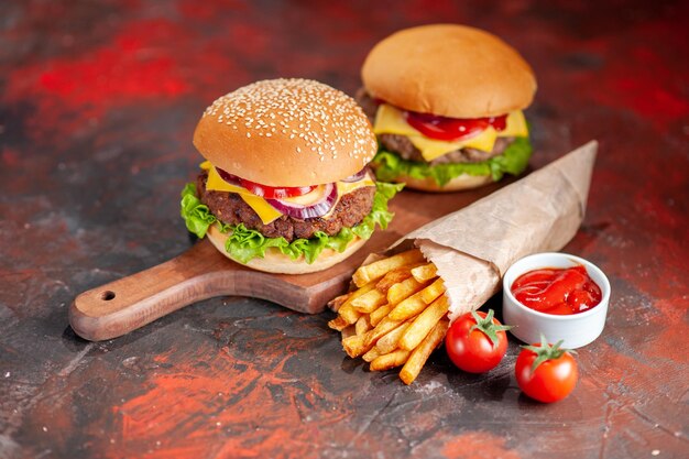 Vista frontal deliciosas papas fritas con hamburguesas con queso sobre fondo oscuro plato de bocadillo comida rápida sándwich cena hamburguesa tostada