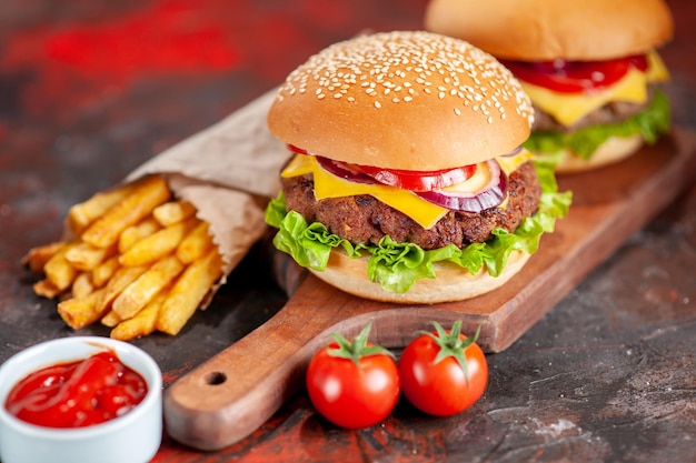 Vista frontal deliciosas papas fritas con hamburguesas con queso sobre fondo oscuro plato de bocadillos cena de hamburguesa tostada de comida rápida