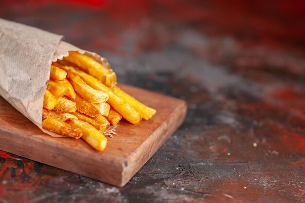 Vista frontal deliciosas papas fritas en la tabla de cortar plato de fondo oscuro comida rápida sándwich tostadas merienda cena