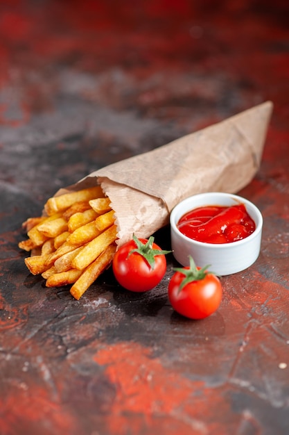 Vista frontal deliciosas papas fritas con tomates sobre fondo oscuro plato de bocadillos comida rápida sándwich cena tostadas hamburguesas