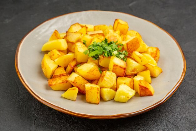 Vista frontal deliciosas patatas fritas dentro de la placa en la mesa oscura