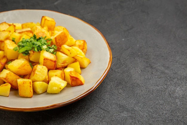 Vista frontal deliciosas patatas fritas dentro de la placa en la mesa oscura