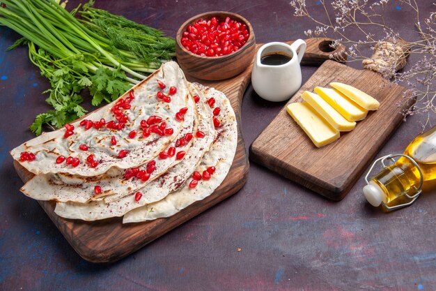 Vista frontal deliciosas pitas de qutabs de carne con granadas frescas en la superficie oscura comida de harina de carne de pita masa