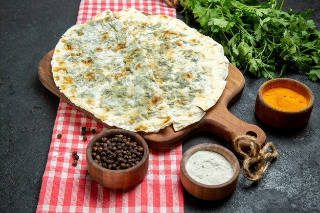 Vista frontal deliciosas rebanadas de masa cocida qutabs con condimentos y verduras en el espacio gris