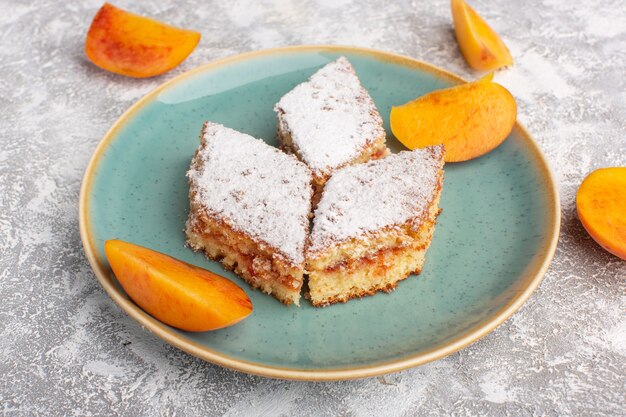 Vista frontal deliciosas rebanadas de pastel con azúcar en polvo y melocotones frescos dentro de la placa sobre la mesa, pastel de galleta de azúcar pastelería dulce hornear