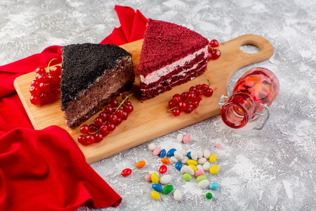 Vista frontal de deliciosas rebanadas de pastel con crema de chocolate y frutas en el escritorio de madera