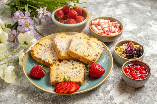 Vista frontal deliciosas rebanadas de pastel con fresas en superficie ligera pastel de pastel dulce de frutas