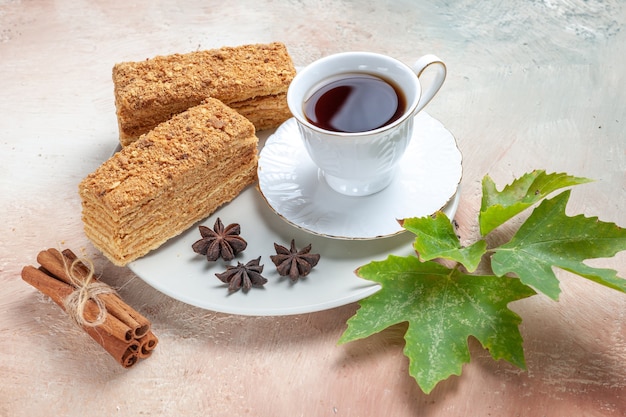 Vista frontal deliciosas rebanadas de pastel con una taza de té en la luz