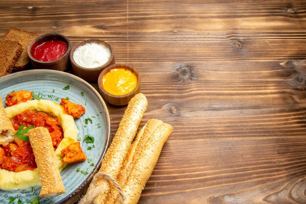 Vista frontal deliciosas rodajas de pollo con puré de patatas y pan en el escritorio de madera patatas comida comida pimiento picante